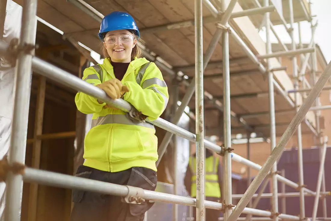 a woman in a hard hat standing on a scaffold.